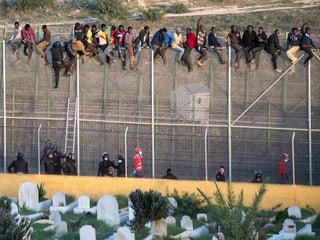 Flüchtlinge sitzen auf dem Grenzzaun im spanischen Melilla.