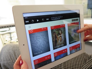 Frau hält iPad in der Hand vorauf die Webseite von «Serial» zu sehen ist.