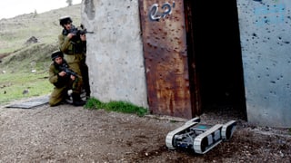 Ein Militärroboter sucht das Gelände ab, auf den Golanhöhen, im Hintergrund zwei israelische Soldaten.