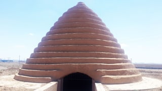 Abgeschufte Kuppel in der Wüste mit einem unterirdischen Eingang.