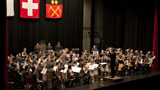 Ein grosses Orchester mit Dirigent auf einer Bühne.