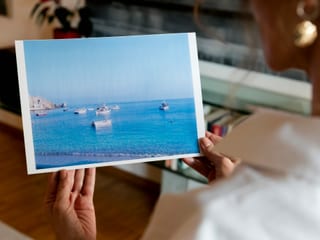 Eine Frau betrachtet ein Bild mit Meer und Schiffen.