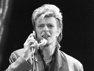 David Bowie telefoniert auf der Bühne.