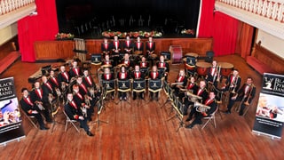 Das gesamte Orchester der Black Dyke Band in schwarz-rot-weiss.