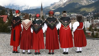 Sechs Jodlerinnen in roten Trachten blicken Richtung Davos Dorf.