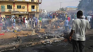 Menschen stehen herum, Rauch liegt in der Luft, auf der Strasse Spuren eines gelöschten Feuers. Menschen stehen herum, Rauch liegt in der Luft, auf der Strasse Spuren eines gelöschten Feuers.
