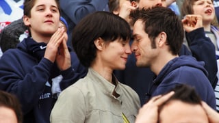 Eine Frau und ein Mann kuscheln im Publikum eines Fussballmatches.
