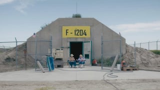 Ein Bunker vor dem ein Mann und eine Frau auf Campingstühlen sitzen. Ein Bunker vor dem ein Mann und eine Frau auf Campingstühlen sitzen.