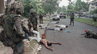 US-Soldaten in Tarnanzügen in einer Strasse in Panama, Verdächtige Personen liegen am Boden.