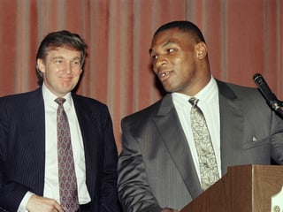 Mike Tyson steht an einem Rednerpult – dahinter ist Donald Trump zu sehen.