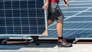 Arbeiter trägt ein Solarpannel