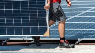 Arbeiter trägt ein Solarpannel Arbeiter trägt ein Solarpannel