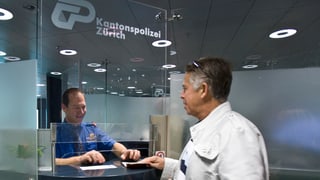 Grenzbeamter am Schalter kontrolliert am Flughafen Zürich den Pass eines Reisenden