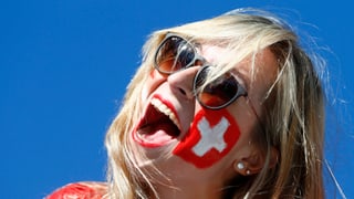 Eine Frau, auf deren Wange ein Schweizerkreuz gemalt ist.