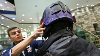 Einem Mann wird in einem Wintersportgeschäft ein Ski-Helm aufgesetzt. Einem Mann wird in einem Wintersportgeschäft ein Ski-Helm aufgesetzt.