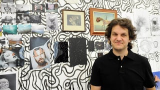 Beni Bischof steht vor verschiedenen kleineren Collagen.