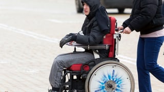Junge im Rollstuhl wird geschoben