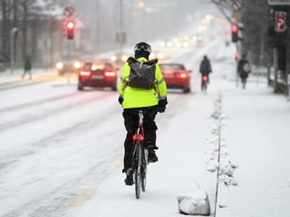 Velofahrer auf schneebedeckter Strasse.