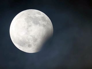 Der helle Vollmond liegt zum Teil im Schatten.