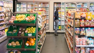 Ein Kunde nimmt sich in einem Convenience-Laden ein Produkt aus dem Kühlschrank.