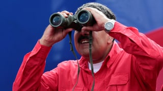 Maduro in rotem Hemd, schaut in ein Fernglas.