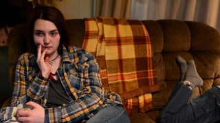 Eine Teenagerin sitzt mit ernstem Gesicht auf einer Couch Eine Teenagerin sitzt mit ernstem Gesicht auf einer Couch