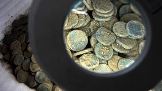 Ein Haufen alter Münzen unter der Lupe.