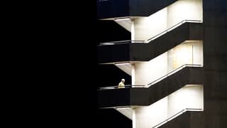 Ein Mensch auf einem beleuchteten Treppenhaus in der Dunkelheit.