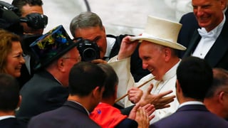 Der Papst setzt sich einen weissen Zylinder auf.