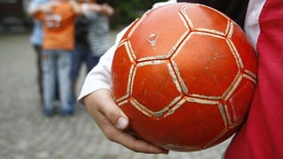 Ein Junge hält ein Ball in der Hand.