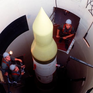 Eine Minuteman-3-Rakete in einem Silo, darum herum stehen Männer.