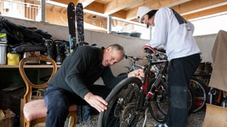 Ein Mann repariert mit einem Jugendlichen in der Garage ein Fahrrad.