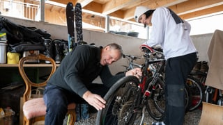 Ein Mann repariert mit einem Jugendlichen in der Garage ein Fahrrad. Ein Mann repariert mit einem Jugendlichen in der Garage ein Fahrrad.