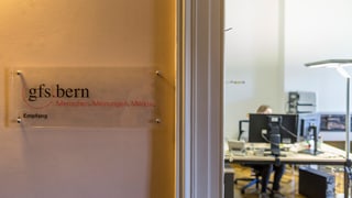Ein Türschild mit dem Logo von gfs.bern vor einem Büro.