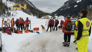 Rettungskräfte stehen im Schnee – hinten ist ein Helikopter zu sehen