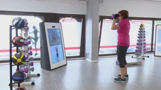 Saal ohne Geräte nur Bildschirm und Hanteln...Frau trainiert Saal ohne Geräte nur Bildschirm und Hanteln...Frau trainiert