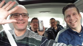 Reto Widmer mit zwei Kollegen und dem Volvo-Medienverantwortlichen auf Testfahrt, Smartphone in der Hand für Selfie, Hände weg vom Steuer. 
