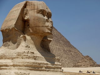 Bild einer grossen, steinernen Sphinx, im Hintergrund eine Pyramide.