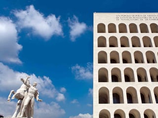 Ein mit Gebäude mit vielen Bogenfenstern, daneben eine Statue eines Mannes mit Pferd.