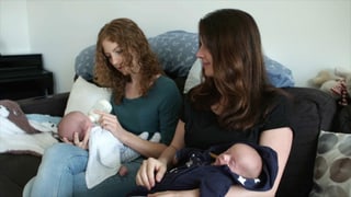 zwei Frauen geben zwei Babies die Flasche zwei Frauen geben zwei Babies die Flasche