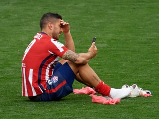 Luis Suarez sitz mit dem Handy auf dem Rasen.