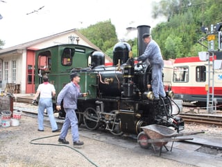 Mitglieder des Vereins Dampfzug Waldenburgerbahn werkeln an der Lok.