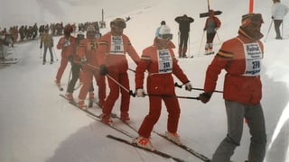 Menschen auf Skiern in roten Anzügen.