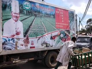 Ein Afrikaner schiebt seinen Handwagen vor einer chinesischen Werbung vorbei. Ein Afrikaner schiebt seinen Handwagen vor einer chinesischen Werbung vorbei.