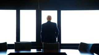 Trump blickt aus einem Gebäude heraus, mit dem Rücken zur Kamera. Trump blickt aus einem Gebäude heraus, mit dem Rücken zur Kamera.