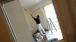 Maler streicht eine Zimmerdecke