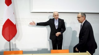 Ueli Maurer und Guy Parmelin vor einer Medienkonferenz, im Hintergrund eine Schweizer Fahne.