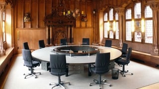 Blick in den Raum, wo die Basler Regierung tagt. Man sieht einen runden Tisch mit 10 Stühlen.