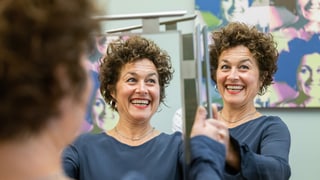 eine Frau mit kurzen Locken hält einen Spiegel hoch eine Frau mit kurzen Locken hält einen Spiegel hoch