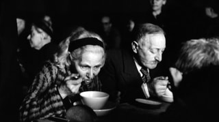 Schwarzweiss Aufnahme einer Frau (links) und eines Mannes, die eine Suppe essen.